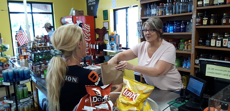 Rudene McCombs, dayshift manager at Bogey's completes a sale to Brooke Austin who was stocking up for the weekend. Bogey's has steadily built its customer base since Little River County left its dry status behind in 2017. Since the shutdown, sales exploded and have not let up since. Customers streamed past their drive-thru starting mid-May and have been coming through the doors since the store reopened May 11. (Staff photo by Junius Stone)