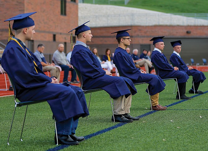 From left, Helias Catholic High School graduates Jacob Andrews, Drew Hoelscher, Ben Pierle, Curtis Rockers and Matthew Roussin sit 6 feet apart from each other for their commencement ceremony Thursday at the Ray Hentges Football Stadium. The school postponed its official graduation ceremony until June but held a special ceremony for the graduates joining the military.