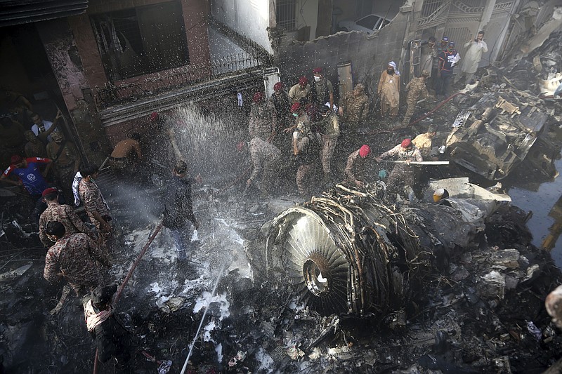 Volunteers look for survivors of a plane that crashed in residential area of Karachi, Pakistan, May 22, 2020. An aviation official says a passenger plane belonging to state-run Pakistan International Airlines carrying more than 100 passengers and crew has crashed near the southern port city of Karachi. (AP Photo/Fareed Khan)