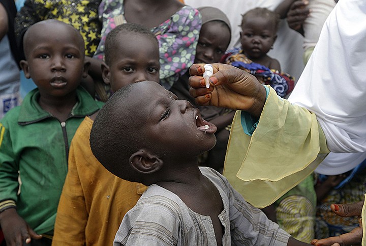 In this Sunday, Aug. 28, 2016 file photo, a health official administers a polio vaccine to children at a camp for people displaced by Islamist Extremist in Maiduguri, Nigeria. The coronavirus pandemic is interrupting immunization against diseases including measles, polio and cholera that could put the lives of nearly 80 million children at risk, according to a new analysis on Friday May 22, 2020, from the World Health Organization and partners. (AP Photo/Sunday Alamba, File)