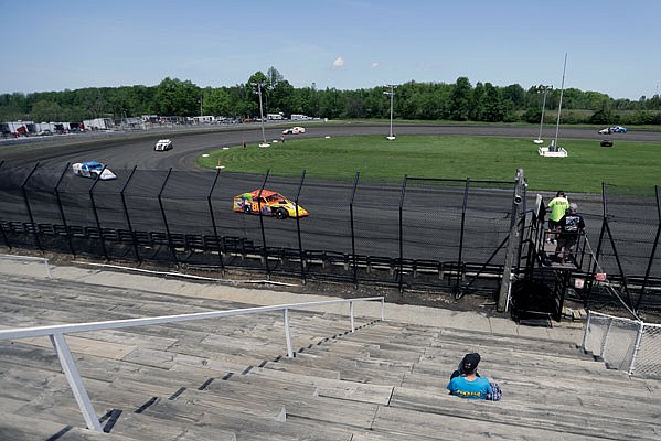 A fan watches as cars practice Sunday on a short dirt track at Gas City I-69 Speedway in Gas City, Ind.