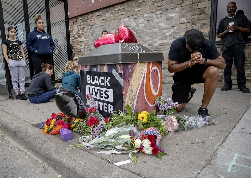 People gather and pray around a makeshift memorial, Tuesday, May 26, 2020, in Minneapolis, near the site where a black man, who was taken into police custody the day before, later died. The FBI and Minnesota agents are investigating the death of a black man in Minneapolis police custody after video from a bystander showed a white officer kneeling on his neck during his arrest as he pleaded that he couldn't breathe.  (Elizabeth Flores/Star Tribune via AP)
