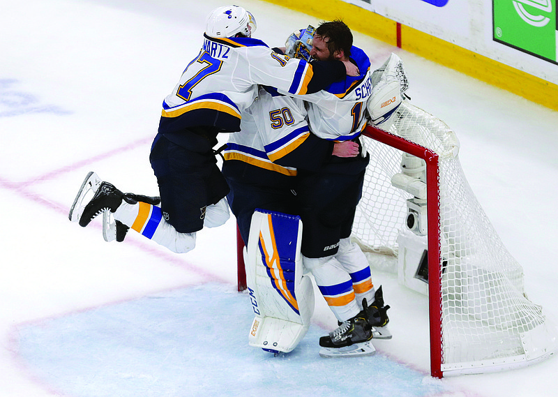 In this June 12, 2019, file photo, Blues teammates Jaden Schwartz (left) and Brayden Schenn mob goaltender Jordan Binnington to celebrate after winning Game 7 of the Stanley Cup Final against the Bruins in Boston.