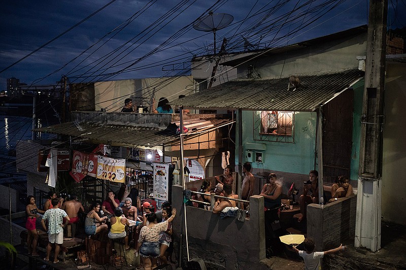 People gather outside a bar in Manaus, Brazil, Sunday, May 24, 2020, amid the new coronavirus pandemic. Although health experts warn that the pandemic is far from over in Manaus, or across the country, national polls show adherence to lockdowns and quarantines falling, and a growing percentage of Brazilians are neglecting local leaders' safety recommendations. (AP Photo/Felipe Dana)