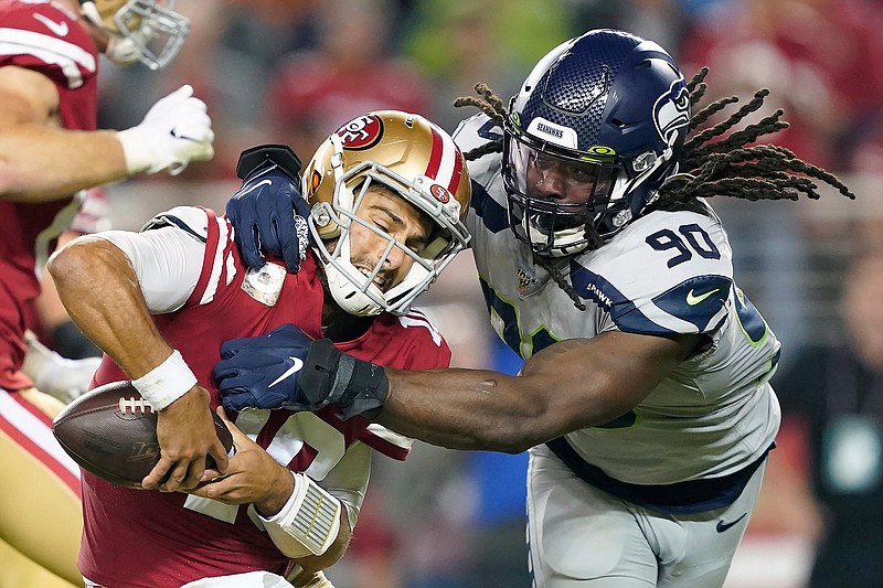 In this Nov. 11, 2019, file photo, San Francisco 49ers quarterback Jimmy Garoppolo, left, avoids being sacked by Seattle Seahawks defensive end Jadeveon Clowney (90) during the second half of an NFL football game in Santa Clara, Calif.  Even with the status of the upcoming season uncertain because of the coronavirus pandemic, teams continue to tinker with their rosters by adding players they hope will help them win — whenever, or if, they actually play. Many believed Clowney would be snatched up by a team desperate for a pass-rushing presence during the first few days of free agency. And, for big-time bucks. Instead, the 2014 No. 1 overall pick is still unsigned two months later and potentially looking at a one-year, prove-it deal. A return to Seattle isn't out of the question. (AP Photo/Tony Avelar, File)