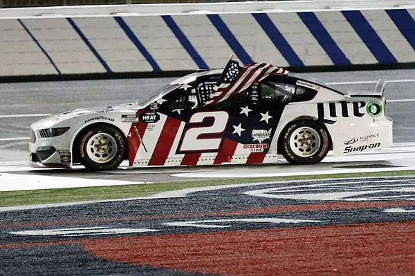 Brad Keselowski holds an American flag early Monday after winning the NASCAR Cup Series race at Charlotte Motor Speedway in Concord, N.C.