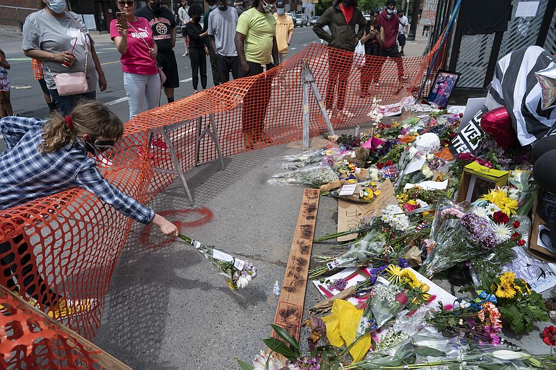 People leave flowers at a makeshift memorial, Wednesday, May 27, 2020, in Minneapolis, near the site where George Floyd, a black man who was taken into police custody on Monday and later died. (Jerry Holt/Star Tribune via AP)