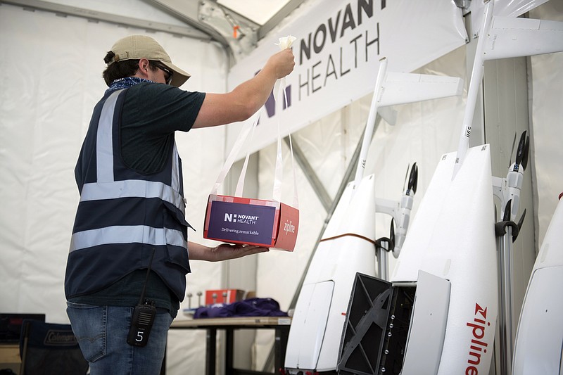 In this undated image provided by Novant Health, a package is prepared to be placed inside a drone for delivery from Novant Health Logistics Center in Kannapolis, N.C., to Novant Health Medical Center in Huntersville, N.C. North Carolina is a testing ground for drone programs involving medical supplies, and this week one of the first deliveries of personal protective equipment in the U.S. was dropped at a hospital by drone. The drones carry up to 4 pounds, and have a round-trip range of 100 miles. (Davis Turner/Novant Health via AP)