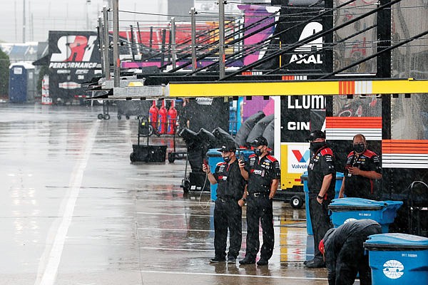 Crew members watch as rain falls before Wednesday night's scheduled NASCAR Cup Series race at Charlotte Motor Speedway in Concord, N.C.