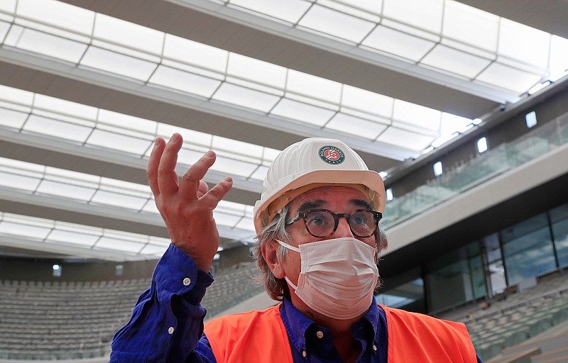 The French Tennis federation's general director Jean-Francois Vilotte wears mask to protect against coronavirus gestures as he speaks during an interview with The Associated Press at Philippe-Chatrier central court with its new retractable roof at Garros stadium in Paris, Wednesday, May 27, 2020. The French open will moving to September from the end of May because of the outbreak of the COVID-19 pandemic. (AP Photo/Michel Euler)