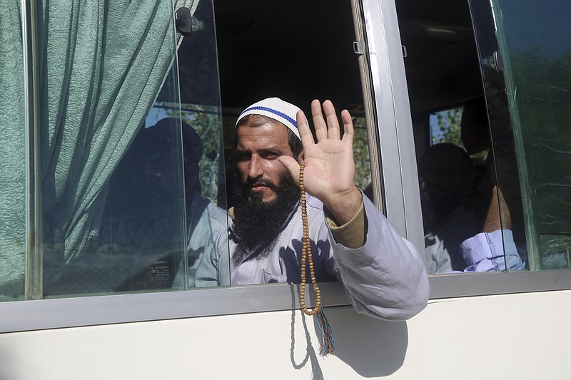 An Afghan Taliban prisoner waves from a bus after being freed from Bagram Prison in Parwan province, Afghanistan, Tuesday, May 26, 2020. The Afghan government freed hundreds of prisoners, its single largest prisoner release since the U.S. and the Taliban signed a peace deal earlier this year that spells out an exchange of detainees between the warring sides. (AP Photo/ Rahmat Gul)