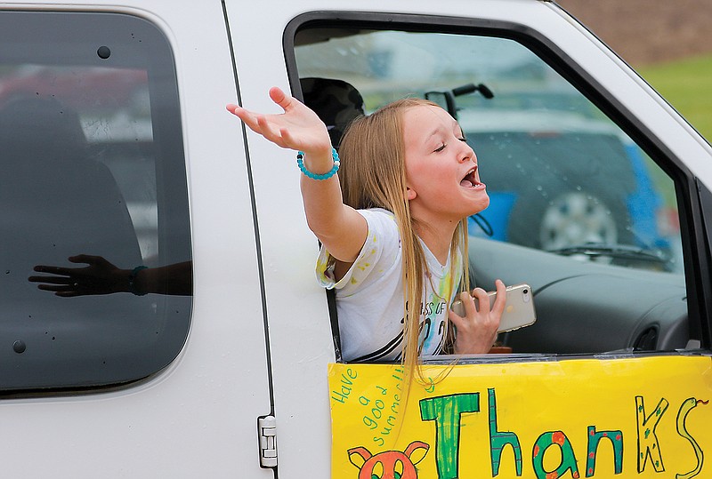 "Thanks, we miss you guys!" fifth-grade graduate Kara Williams yells out the passenger window of a car during the end-of-year drive-by parade past Pioneer Trail Elementary School. Kara and her friend, Briley Gage, went to the parade together and gave their fifth-grade teacher, Paige Siebeneck, a unique end-of-year gift: a ceramic pig statue and a small potted cactus.