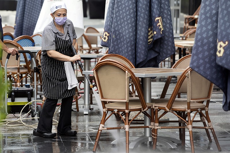 In this May 27, 2020, photo, a worker at Brasserie Beck, a restaurant along K Street in downtown Washington, power washes the outdoor seating area. The nation's capital is starting to reopen, Starting May 29, a tiny slice of pre-pandemic normality starts returning to the city as the three-month old coronavirus stay-home order is replaced by the first phase of a reopening plan(AP Photo/Jon Elswick)