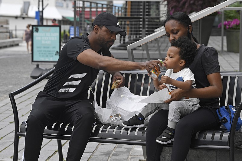 John Price and Bijan Black have lunch with their son Parker Price, 2, all of Seat Pleasant, Md., at the Wharf area in Washington, Friday, May 29, 2020. This was their first time venturing out since the coronavirus pandemic started. (AP Photo/Susan Walsh)