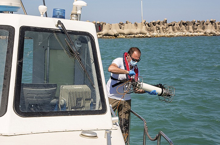 In this picture taken on Thursday, May 21, 2020, Italian Lazio region's environmental agency biologist Salvatore De Bonis shows how they perform tests on sea water during an interview with The Associated Press on a Coast Guard boat off Fiumicino, near Rome. Preliminary results from a survey of seawater quality during Italy's coronavirus lockdown indicate a sharp reduction in pollution from human and livestock waste in the seas off Rome. Authorities stressed it was too soon to give the lockdown sole credit for the change. (AP Photo/Domenico Stinellis)