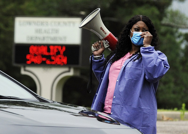 In this May 27, 2020, photo, health care worker Tonya Wilkes adjusts her mask while working at a Lowndes County coronavirus testing site in Hayneville, Ala. Experts say Lowndes County and nearby poor, mostly black counties in rural Alabama are now facing a "perfect storm" as infections tick up: a lack of access to medical care combined with poverty and the attendant health problems that can worsen the outcomes for those who become sick. (AP Photo/Jay Reeves)