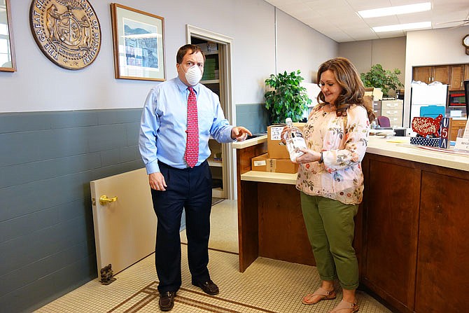 FILE: Callaway County Clerk Ronda Miller, right, looks at a large bottle of hand sanitizer delivered (among other PPE) by Missouri Secretary of State Jay Ashcroft in mid-May..