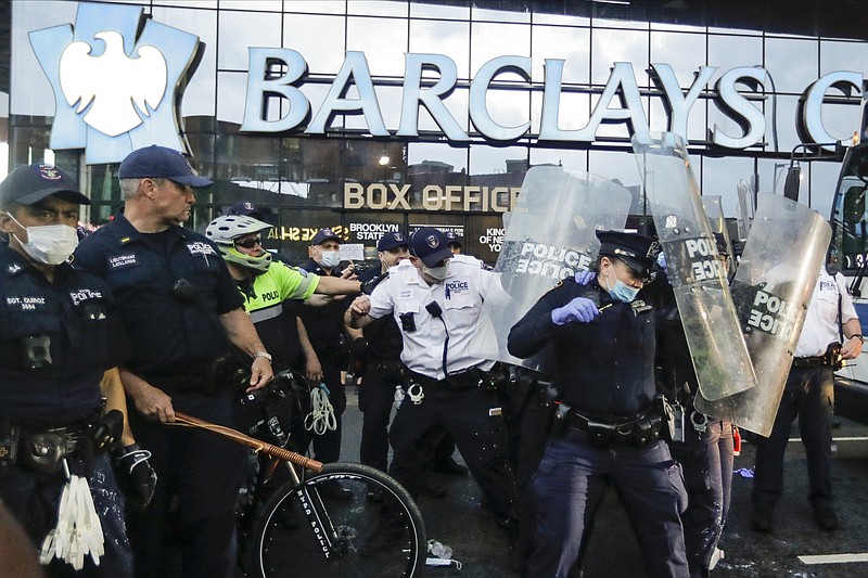 Police officers protect themselves with shields as protesters throw debris during a rally Friday, May 29, 2020, in the Brooklyn borough of New York, at the Barclays Center over the death of George Floyd, a black man who was in police custody in Minneapolis. (AP Photo/Frank Franklin II)