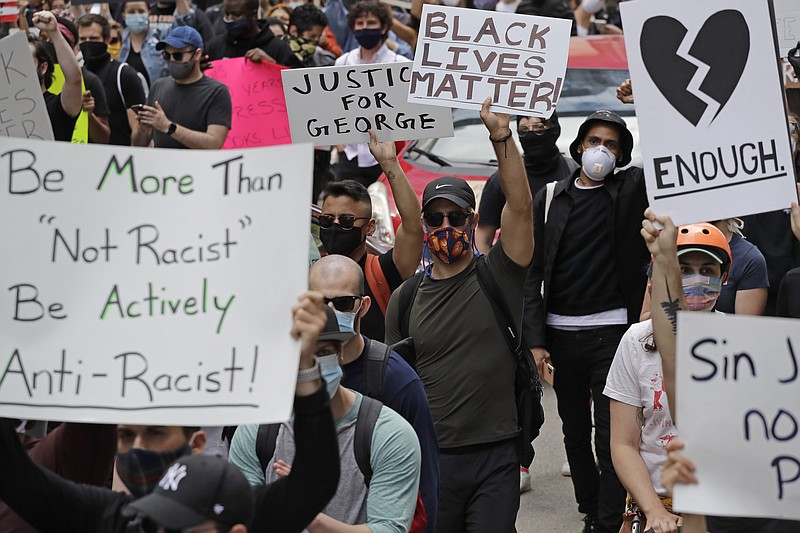 People hold signs as they march in Chicago, Saturday, May, 30, 2020, during a protest over the death of George Floyd. Floyd died in Minneapolis police custody on May 25. (AP Photo/Nam Y. Huh)