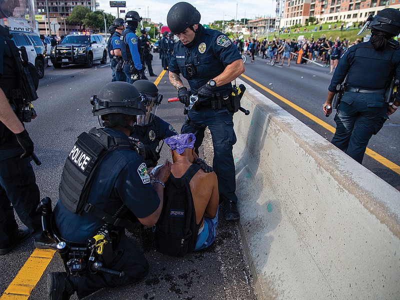 Austin Police help a protester who was hit by pepper spray Saturday while demonstrators shut down southbound Interstate 35 in Austin in response to the Memorial Day death of George Floyd while in police custody in Minneapolis.