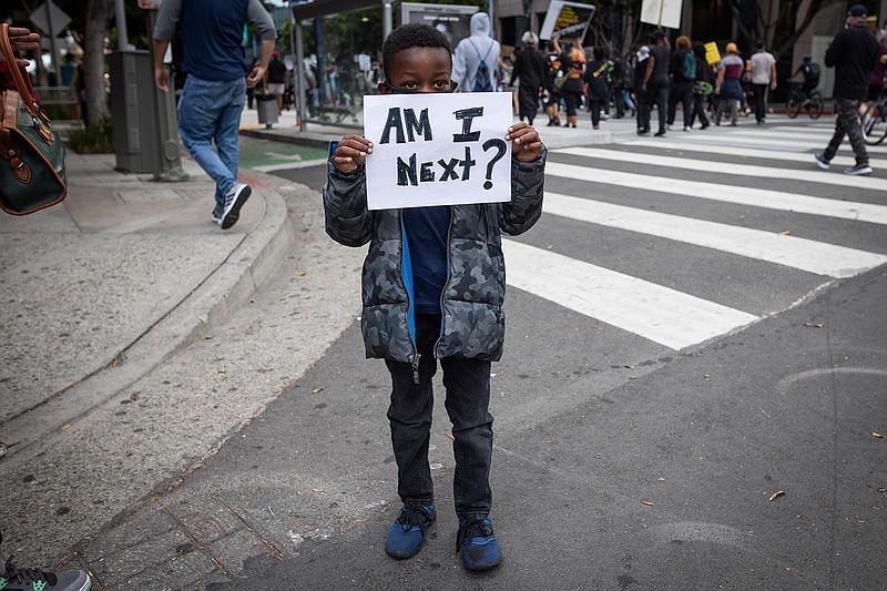 A boy holds a sign during a protest in downtown Los Angeles, Friday, May 29, 2020, over the death of George Floyd, who died in police custody on Memorial Day in Minneapolis. (AP Photo/Christian Monterrosa)