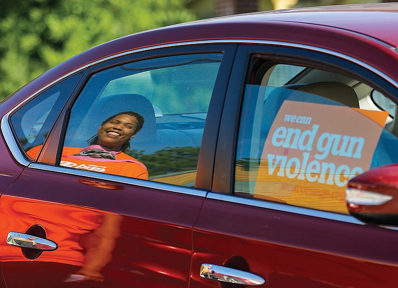 Alicia Edwards, reflected in a Moms Demand Action member's car, walks up to unload groceries from the trunk during the "food pantry parade" Tuesday, June 2, 2020. The food was given to Building Community Bridges.