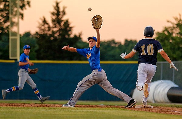 Fatima first baseman Jared Markway reaches to catch the ball before Peyton Huddleston of Helias makes it to the base during the second game of Tuesday night's doubleheader at the American Legion Post 5 Sports Complex.