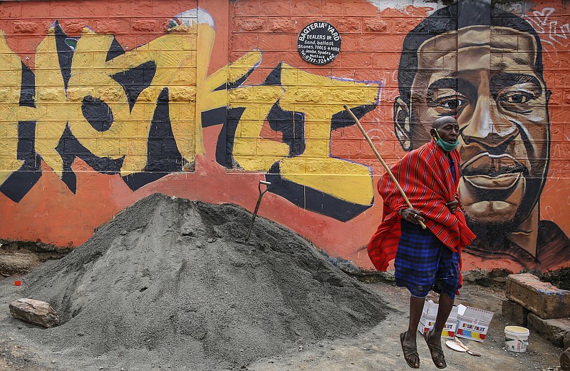 FILE - In this Wednesday, June 3, 2020 file photo a Maasai man, who said he had seen videos on Facebook about protests in the U.S. over the death of George Floyd, jumps next to a new mural painted this week showing Floyd with the Swahili word "Haki" meaning "Justice", in the Kibera slum, or informal settlement, of Nairobi, Kenya. Since George Floyd's death in the U.S. state of Minnesota last week, his face has been painted on walls from Nairobi, Kenya to Idlib, Syria. Floyd's name has been inked on the shirts of soccer players and chanted by crowds from London and Cape Town to Tel Aviv and Sydney. (AP Photo/Brian Inganga, File)
