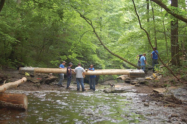 Young Hoosier Conservation Corps (YHCC) workers build a hiking bridge from natural materials at Clifty Falls State Park in Jefferson County, Ind.