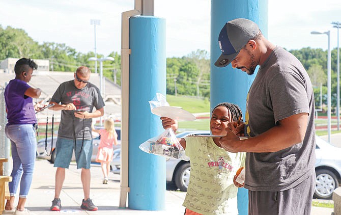 A Boys & Girls Club member shows her dad the artwork she made Friday during pickup at the Boys and Girls Club of Jefferson City. June 1-5 was the first week of summer programming for the club. On Friday, all members received a glazed doughnut and Buddy Pack full of non-perishable goods for the weekend.