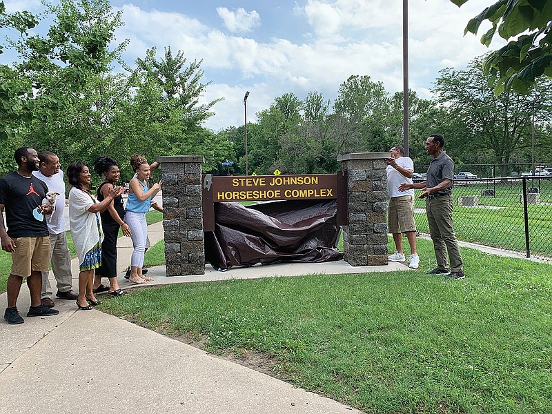 Steve Johnson, far right, and his family and friends unveil the new sign naming the horseshoe complex at Washington Park as the "Steve Johnson Horseshoe Complex."