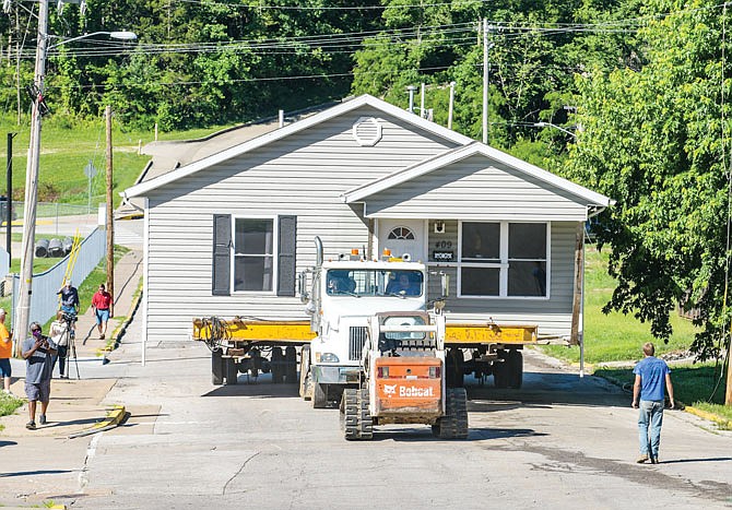 James Jonassen, of Jonassen Structural Movers of Hartville, drives the truck up the hill of Jackson Street as crews from local utility companies make sure the power, telephone and internet lines are securely out of reach as the house is moved up the hill. The house was built in 2012 at 409 Stadium to 1100 block of Jackson Street as a River CIty Habitat for Humanity home. The house was moved Thursday and after being placed, was raised and cribbage placed under it. A foundation will soon be poured under the house, and then it'll be lowered onto it.