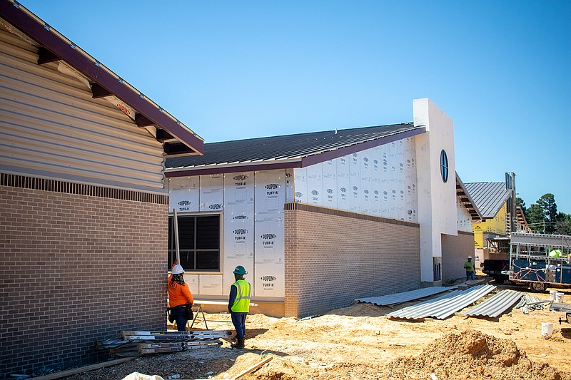 Workers stand next to the outside of a pod at the Margaret Fischer Davis Elementary School. Each grade level gets a section of the building for its classrooms and activity areas. (Staff photo by Sara Vaughn)

