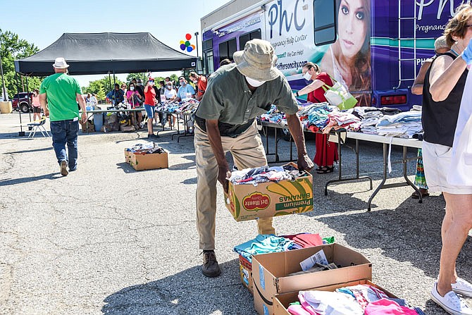 Volunteer Charles Pannell carries a box of sorted clothes Friday, June 12, 2020, during a clothing giveaway at the Samaritan Center in the parking lot next to Save-a-Lot at 1228 E. McCarty St. Due to being closed except for food pickup, the center had an abundance of clothing.