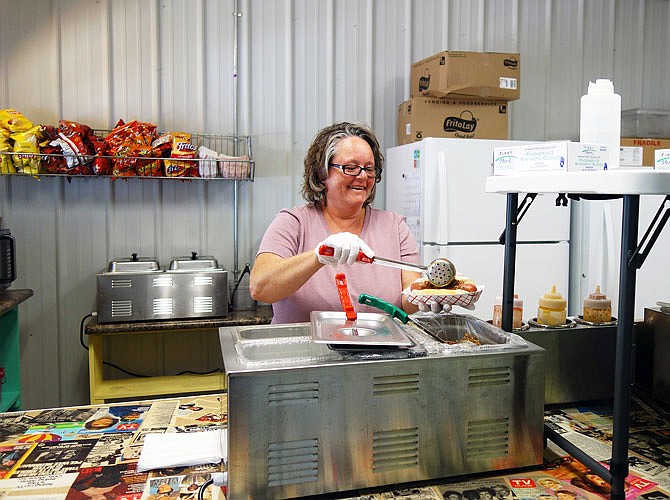 Cindy Baker, owner of The Spot, ladles tavern meat over the eatery's signature Spot Coney Dog. The quarter-pound Nathan's Famous dog is topped with seasoned ground beef and cheese sauce. It can be "Whammy"-d — smothered with bacon and onions caramelized in Coke — for an additional $2.