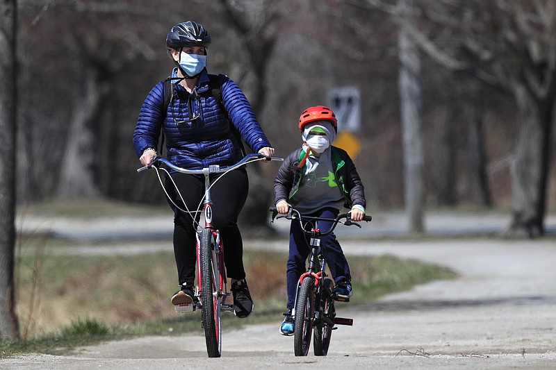 FILE-In this Wednesday, April 8, 2020, photo, bicyclists wear pandemic masks while riding in Portland, Maine. Bicycle sales have surged as shut-in families try to find a way to keep kids active at a time of lockdowns and stay-at-home orders during the coronavirus pandemic. (AP Photo/Robert F. Bukaty)