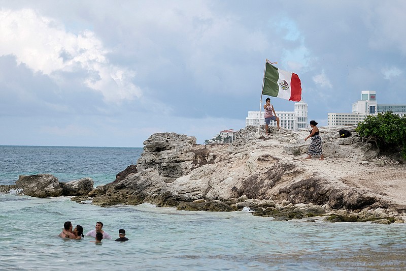 People spend time Saturday, June 13, 2020, on the coast of Cancun, Mexico. An irony of the coronavirus pandemic is that the idyllic beach vacation in Mexico in the brochures really does exist now: the white sand beaches are sparkling clean and empty on the Caribbean coast. 