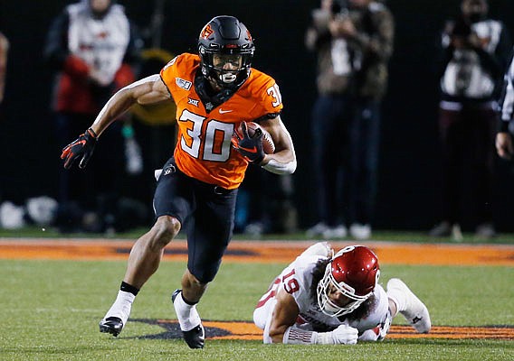 In this Nov. 30, 2019, file photo, Oklahoma State running back Chuba Hubbard sprints past Oklahoma linebacker Caleb Kelly during a game in Stillwater, Okla.