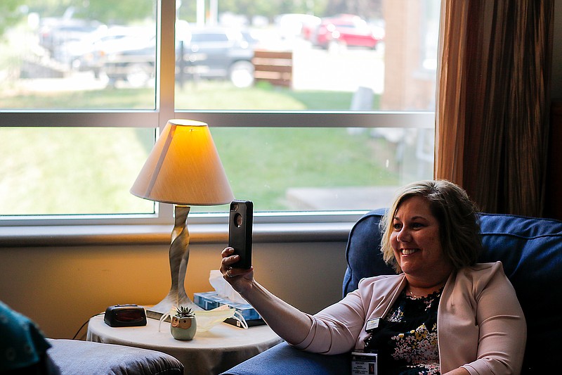 Heather Johns uses her phone to telecommunicate with Barbara Price-Boucher, who is sitting across the room from her, to demonstrate how a teleconference between a patient and a therapist could go on Friday at Capital Region Medical Center's Southwest Campus in Jefferson City. Teleconferenced therapy sessions can be held over the phone, on a smart device like an iPad or via laptop or computer.