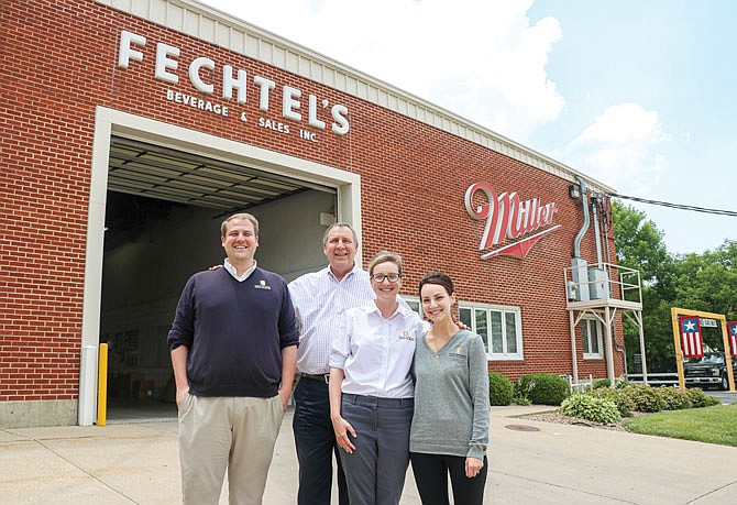 From left, Andy, Bernie, Morgan and Maggie Fechtel smile together Friday outside of Fechtel's Beverage & Sales Inc. Andy, Morgan and Maggie are the children of Bernie. Bernie took control of the family business from his father.