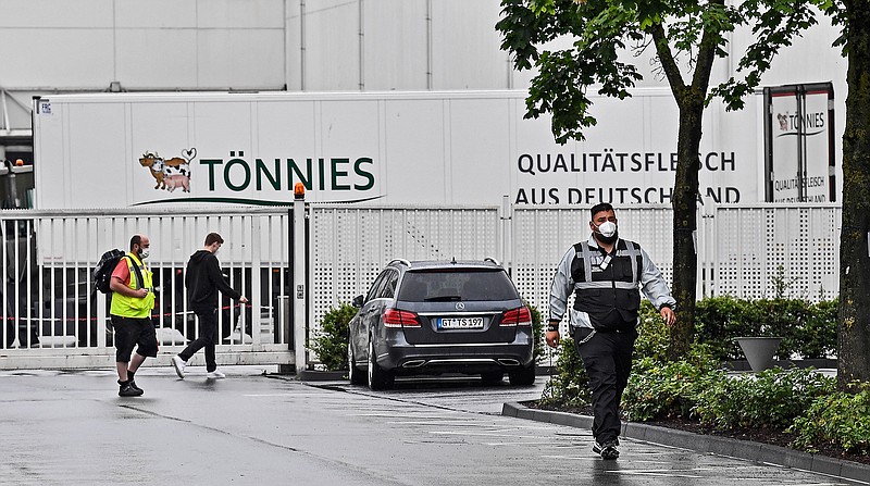 A member of  the security walks in front of the Toennies meatpacking plant, Europe's biggest slaughterhouse, in Rheda-Wiedenbrueck, Germany, Thursday, June 18, 2020. Hundreds of new COVID-19 cases are linked to a large meatpacking plant, officials ordered the closure of the slaughterhouse, as well as isolation and tests for everyone else who had worked at the Toennies site — putting about 7,000 people under quarantine. (AP Photo/Martin Meissner)