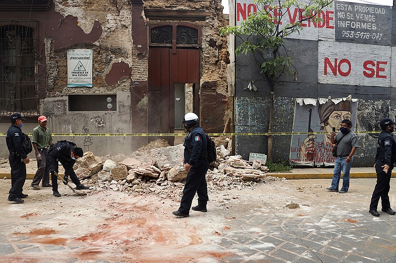 A policeman removes rubble from a building damaged by an earthquake in Oaxaca, Mexico, Tuesday, June 23, 2020. The earthquake was centered near the resort of Huatulco, in the southern state of Oaxaca. (AP Photo/Luis Alberto Cruz Hernandez)