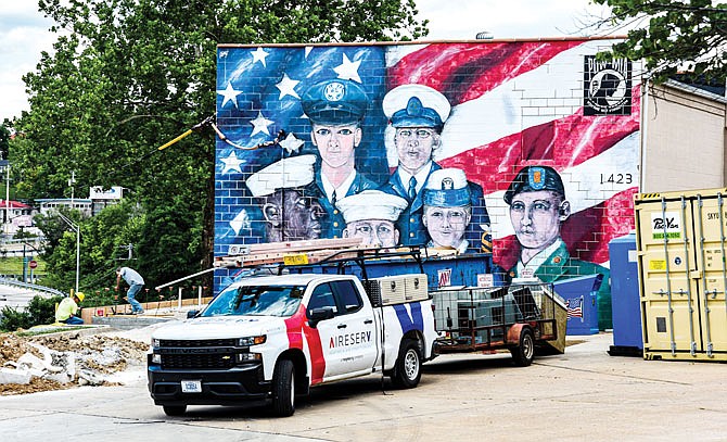 Behind storage containers and work trucks, the mural painted several years ago by art students from Helias Catholic High School can be seen. It features a representative of each of the United States military branches. Jefferson City's Roscoe Enloe American Legion Post 5 is looking for an artist to complete a patriotic mural on its building on Tanner Bridge Road.