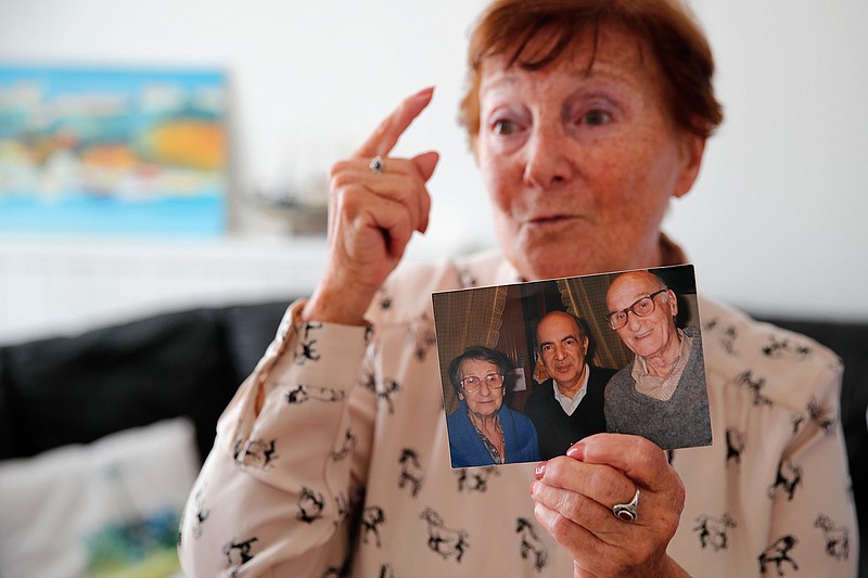 In this photo taken on Friday June 5, 2020, Monette Hayoun displays a photo of her late severely disabled 85-year-old brother, Meyer, center in the picture, flanked with her parents, during an interview in Ivry sur Seine, south of Paris. Families whose elders died behind the closed doors of homes in lockdown are filing wrongful death lawsuits, triggering police investigations. One suit focuses on the death of Meyer Haiun, a severely disabled 85-year-old in a Paris home managed by a Jewish charitable foundation headed Eric de Rothschild, scion of Europe's most famous banking dynasty. (AP Photo/Francois Mori)
