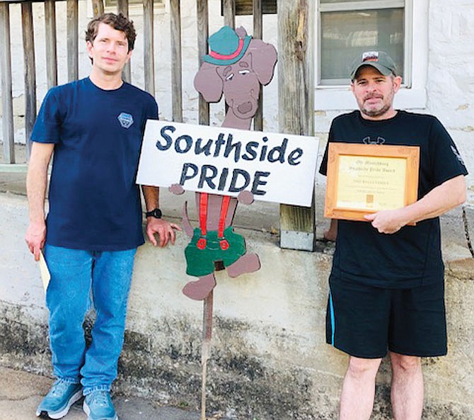 Sam Wells, left, and Tim Wells display their Southside Pride Appearance Award and unique large dachshund yard sign in front of the home at 908 Broadway St.