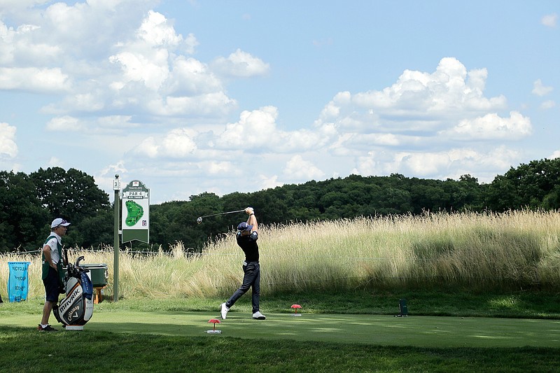 Matt Wallace, right, of England, tees off on the third hole as caddie David McNeilly looks on during the second round of the Travelers Championship golf tournament at TPC River Highlands, Friday, June 26, 2020, in Cromwell, Conn. Wallace is playing the second round by himself after two other golfers in his group, Denny McCarthy and Bud Cauley, withdrew from the tournament. McCarthy told Golfchannel.com that he withdrew from the tournament after feeling sick Thursday night and testing positive for the coronavirus on Friday. Cauley, who played with McCarthy on Thursday, also withdrew before Friday's second round. McCarthy became the third PGA Tour player to test positive for the virus since its restart and the second this week, joining Cameron Champ who withdrew on Tuesday. Nick Watney withdrew just before the second round of last week's RBC Heritage Championship. (AP Photo/Frank Franklin II)