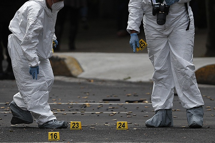Forensic investigators tag cartridges at the scene where the Mexican capital's police chief was attacked by gunmen in Mexico City, Friday, June 26, 2020. Heavily armed gunmen attacked and wounded Omar Garcia Harfuch in an operation that left several dead. (AP Photo/Rebecca Blackwell)