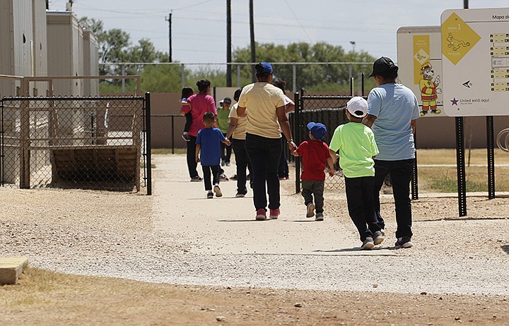 In this Aug. 23, 2019, file photo, immigrants seeking asylum hold hands as they leave a cafeteria at the ICE South Texas Family Residential Center in Dilley, Texas. The isolation of at least three families at the U.S. Immigration and Customs Enforcement's detention center in Dilley, has raised new fears of the coronavirus spreading through a facility that has long been accused of providing substandard medical care. (AP Photo/Eric Gay, File)