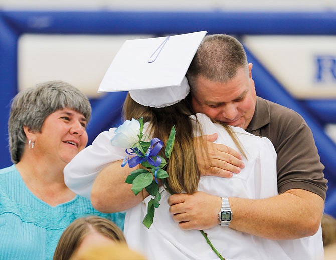 Chuck and Anne Brennecke hug their daughter, Holly, on Saturday after she gave them her rose during Russellville High School's graduation ceremony.