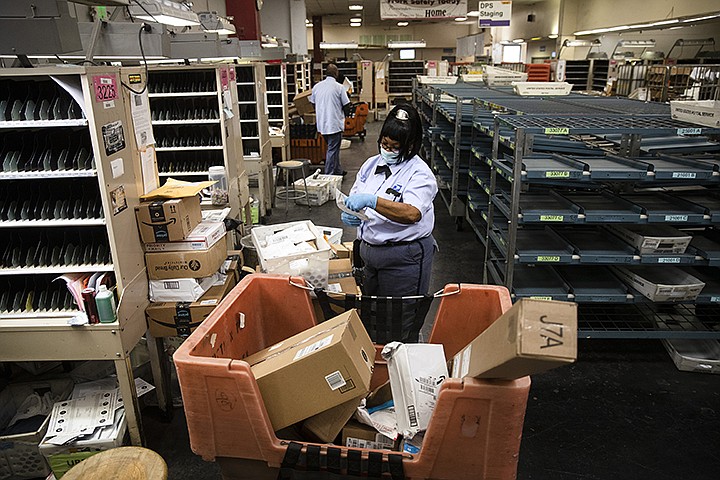 In this Wednesday, May 6, 2020, photo, United States Postal Service carrier Henrietta Dixon sorts mail to be delivered before she sets out on her route in Philadelphia. Dixon has been with the post office for nearly 30 years, the last nine on her current route. (AP Photo/Matt Rourke)